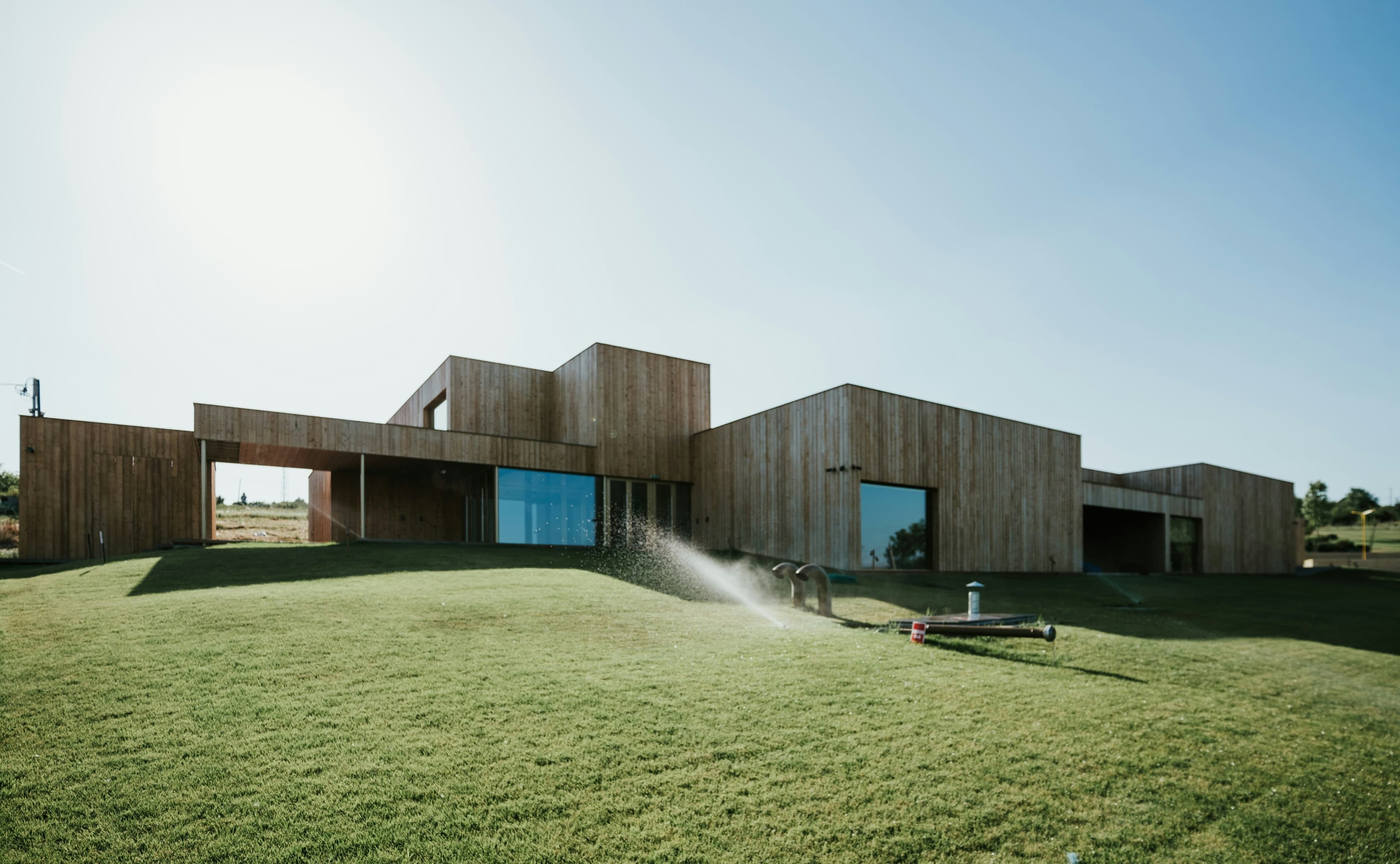 Low timber clad house on a sloping lawn