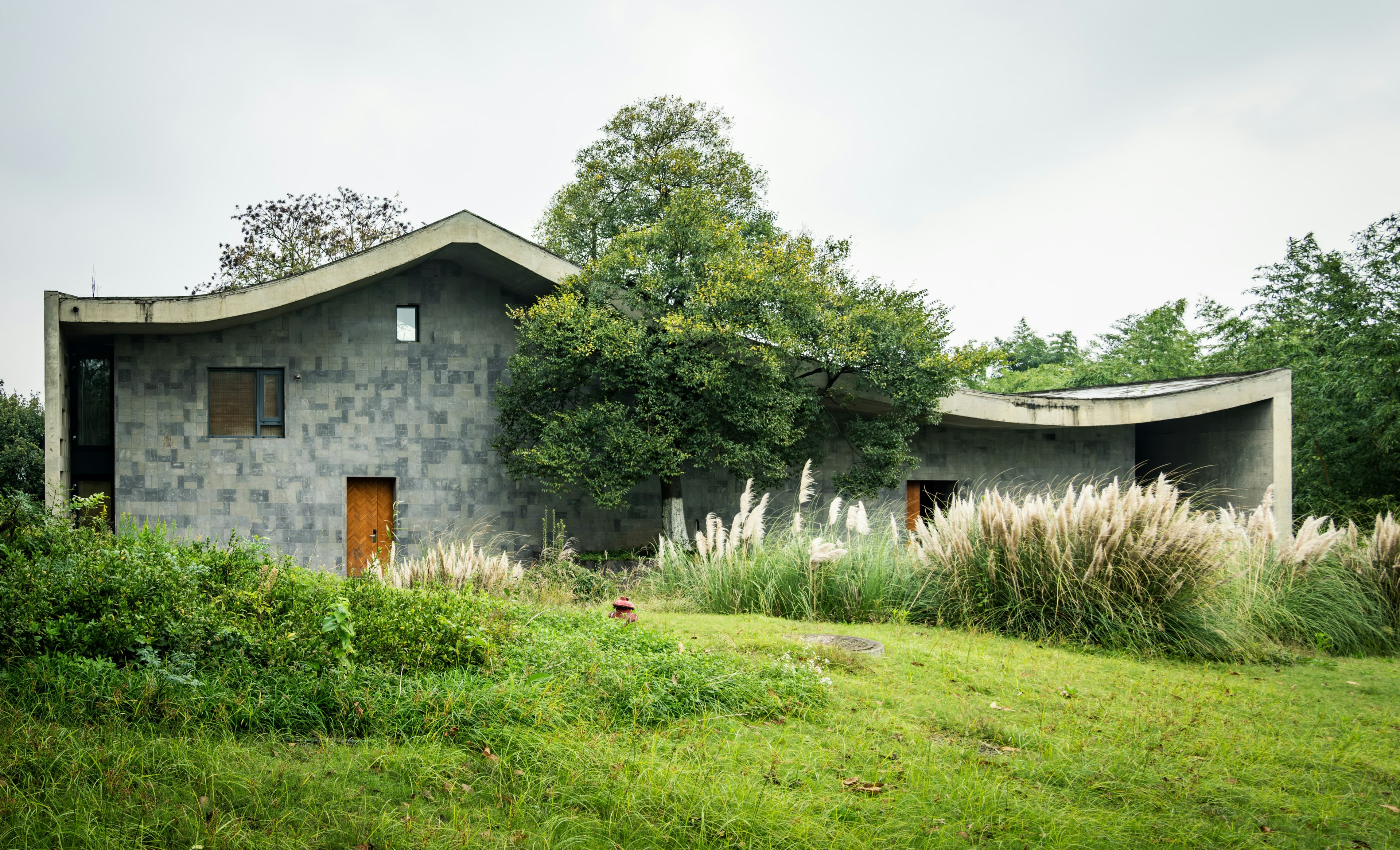 Stone house with a curved green roof in long grass